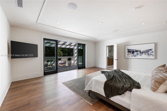 bedroom with access to exterior, hardwood / wood-style flooring, and ensuite bath