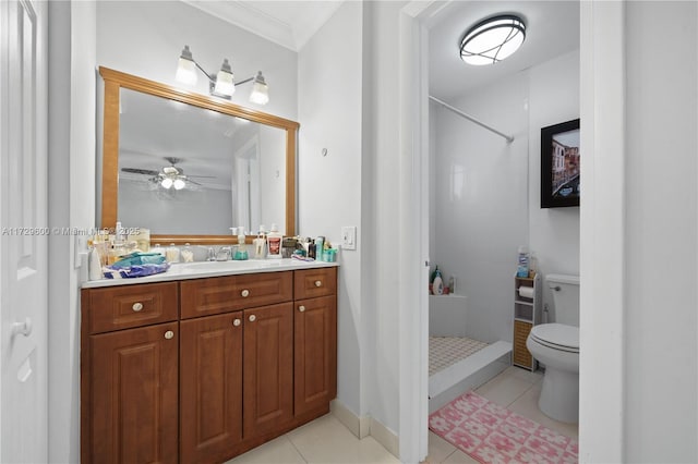 bathroom with toilet, vanity, tile patterned flooring, tiled shower, and crown molding