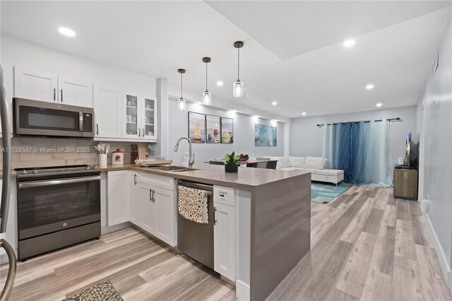 kitchen featuring sink, white cabinetry, stainless steel appliances, and hanging light fixtures