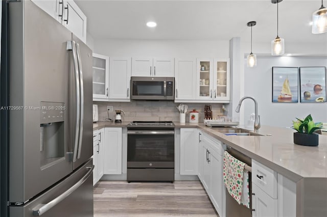 kitchen with decorative light fixtures, sink, stainless steel appliances, and white cabinetry