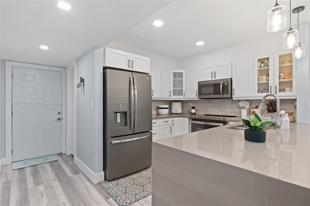 kitchen with stainless steel appliances, backsplash, pendant lighting, white cabinets, and sink