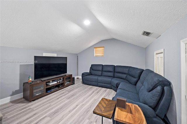 living room with lofted ceiling, light wood-type flooring, and a textured ceiling