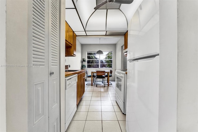 kitchen with light tile patterned flooring, white appliances, and sink