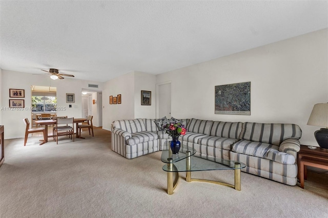 living room with ceiling fan, carpet, and a textured ceiling