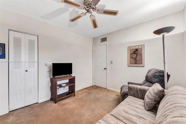 carpeted living room with ceiling fan and a textured ceiling