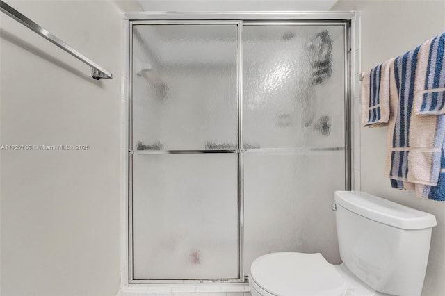 bathroom with a shower with door and toilet