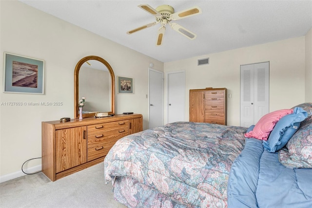 bedroom with a closet, ceiling fan, light colored carpet, and a textured ceiling