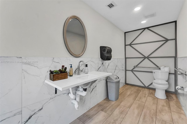 bathroom featuring sink, toilet, and tile walls