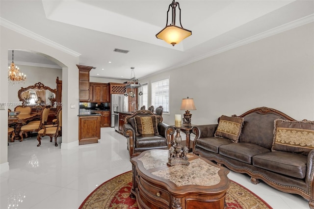 tiled living room with a notable chandelier, crown molding, and a tray ceiling