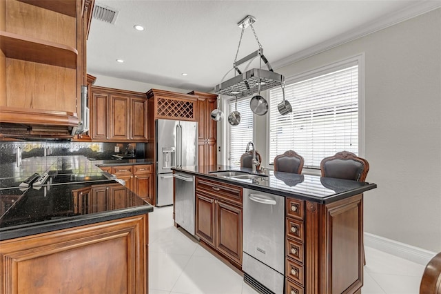 kitchen with tasteful backsplash, sink, appliances with stainless steel finishes, and an island with sink