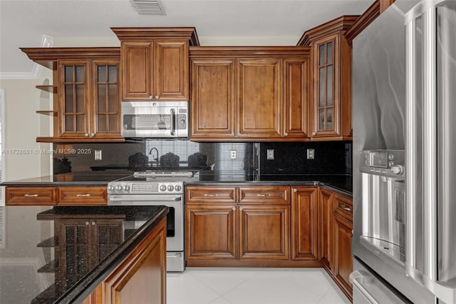 kitchen featuring decorative backsplash, dark stone counters, light tile patterned flooring, and stainless steel appliances