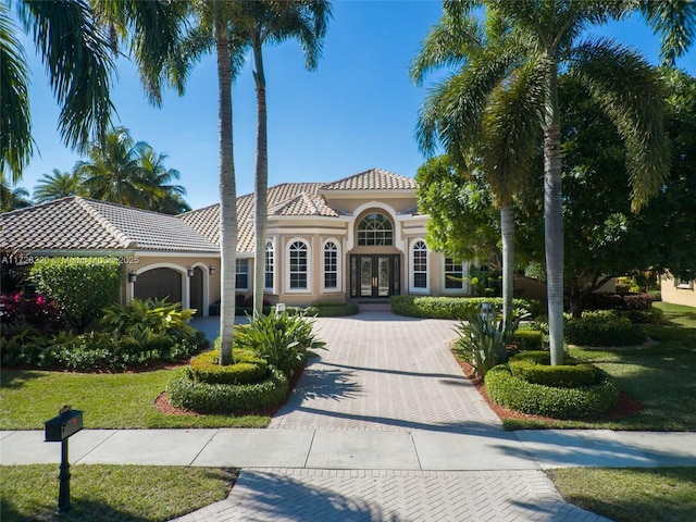 mediterranean / spanish-style home featuring french doors, a garage, and a front lawn