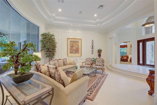 tiled living room featuring crown molding, a tray ceiling, and decorative columns