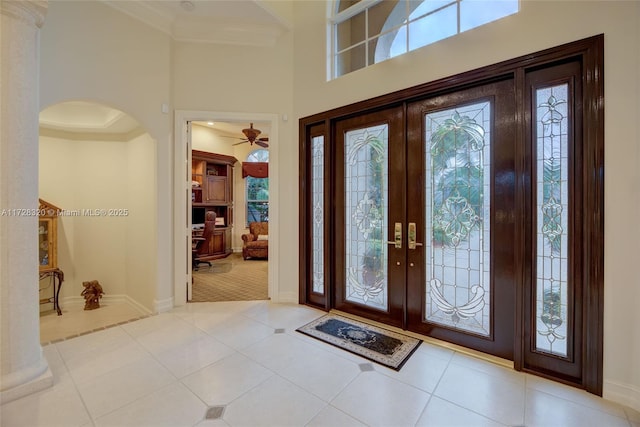 foyer entrance with french doors, a towering ceiling, a wealth of natural light, and light tile patterned floors