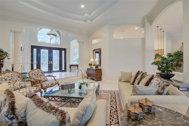 living room with ornamental molding, tile patterned floors, a tray ceiling, and decorative columns