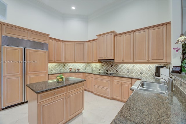 kitchen with sink, light tile patterned floors, paneled fridge, a towering ceiling, and dark stone counters