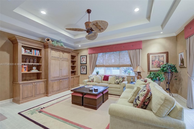 living room with a raised ceiling, ornamental molding, light colored carpet, and ceiling fan