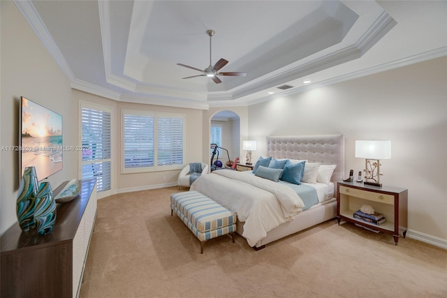 bedroom featuring ceiling fan, ornamental molding, a raised ceiling, and light colored carpet