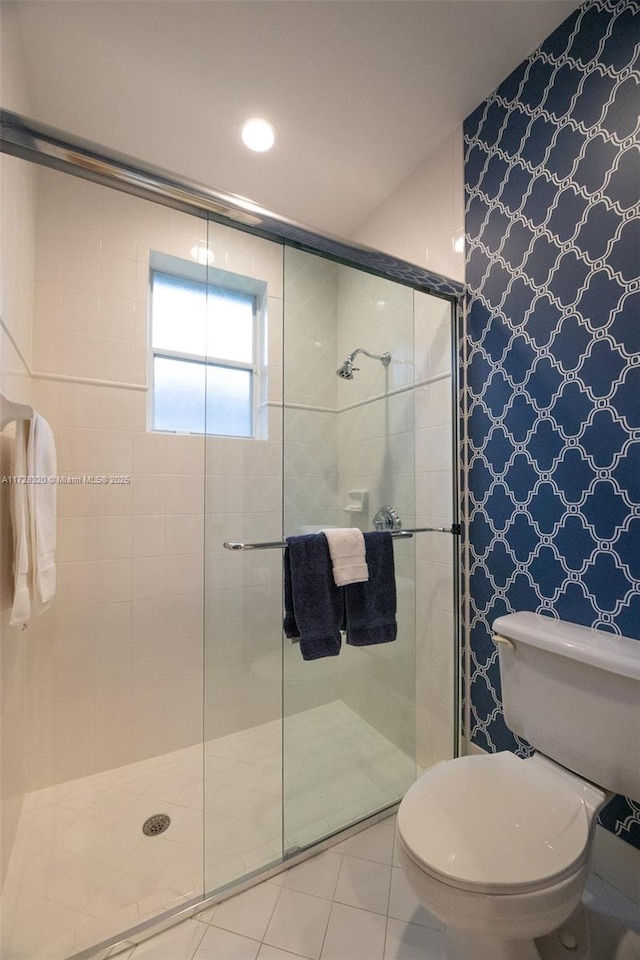 bathroom with toilet, tile patterned flooring, and a shower with door