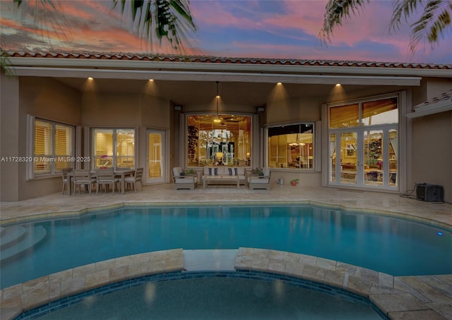 pool at dusk featuring an outdoor living space and a patio area