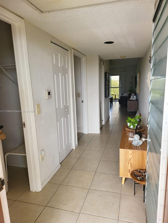 hall with light tile patterned floors and a textured ceiling