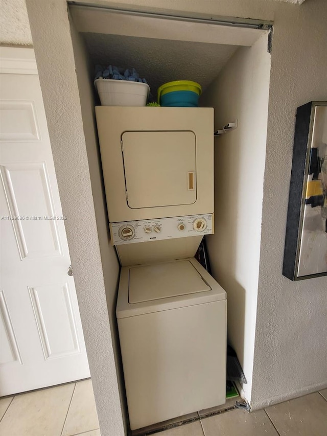 laundry room with stacked washing maching and dryer and light tile patterned flooring