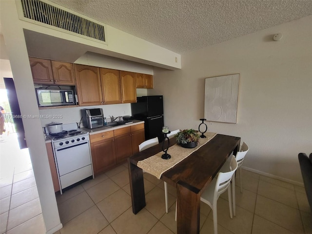 kitchen with sink, a textured ceiling, black appliances, and light tile patterned flooring