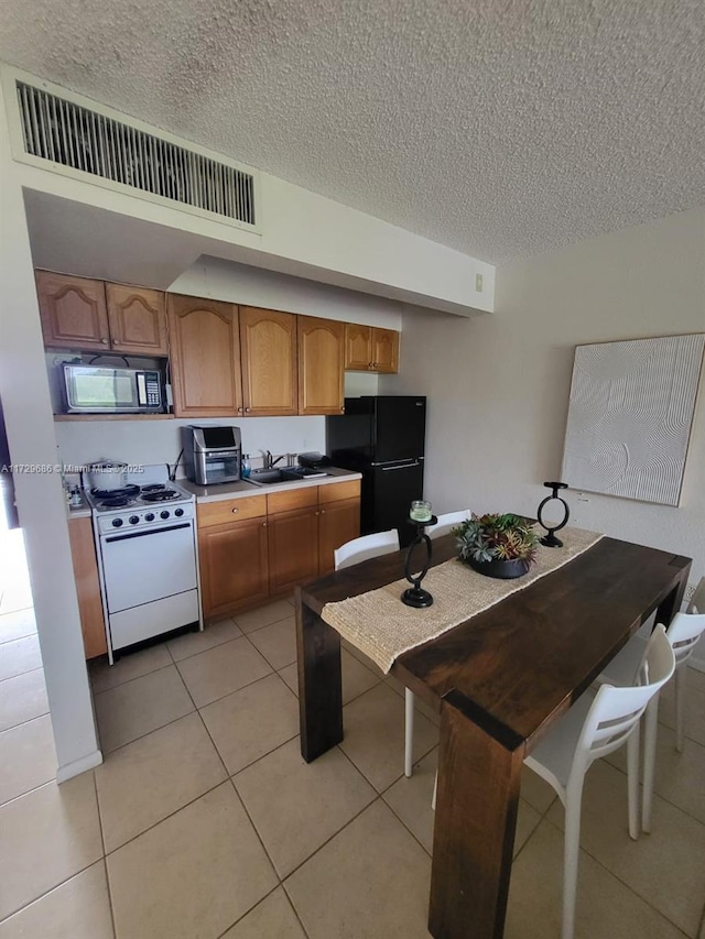 kitchen with black appliances, light tile patterned floors, sink, and a textured ceiling