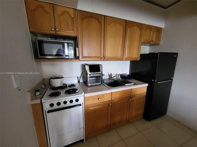 kitchen featuring light tile patterned flooring, sink, white range with electric stovetop, and black refrigerator