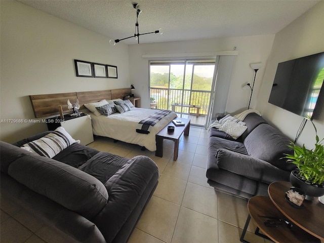 bedroom featuring access to exterior, a textured ceiling, and light tile patterned floors