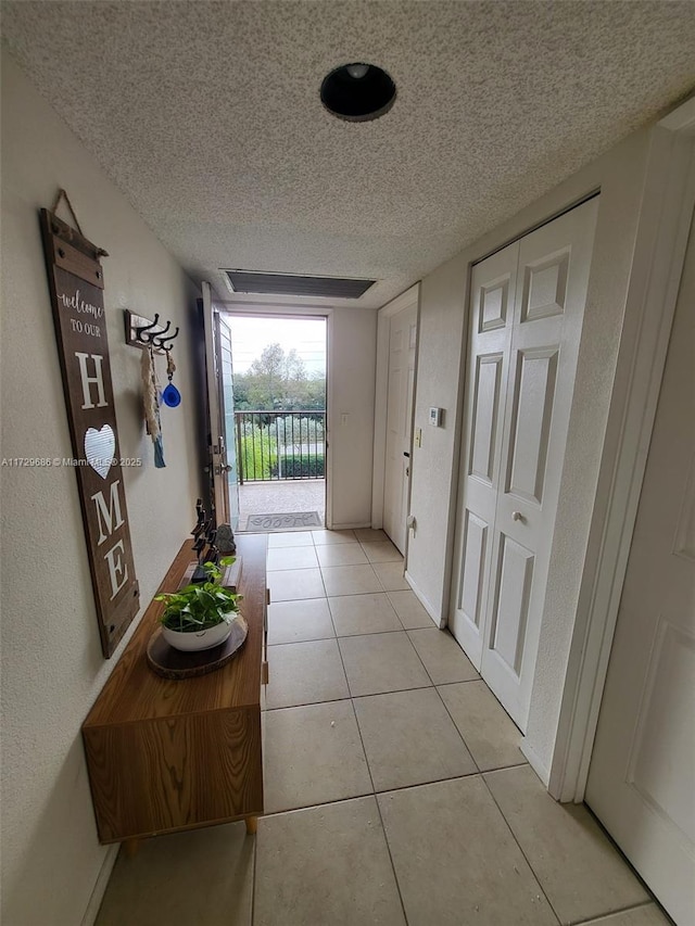 hallway featuring a textured ceiling and light tile patterned floors