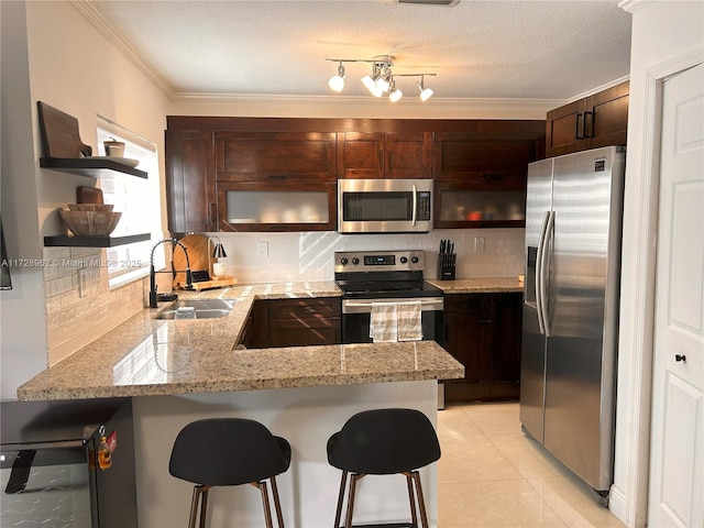 kitchen featuring appliances with stainless steel finishes, tasteful backsplash, a kitchen breakfast bar, light stone counters, and sink