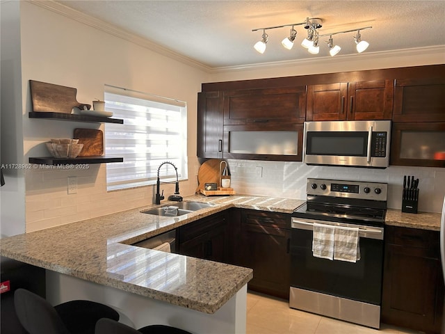 kitchen with kitchen peninsula, sink, appliances with stainless steel finishes, a breakfast bar area, and light stone counters