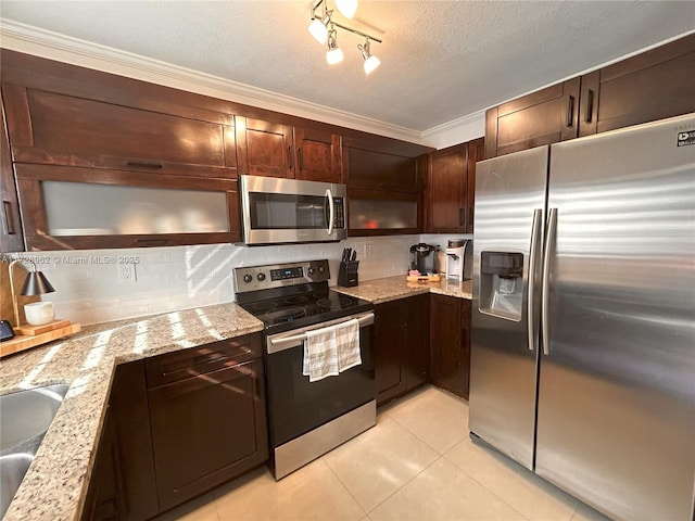 kitchen with light tile patterned floors, appliances with stainless steel finishes, light stone countertops, a textured ceiling, and crown molding