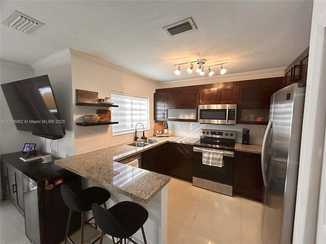 kitchen featuring a kitchen bar, kitchen peninsula, appliances with stainless steel finishes, a textured ceiling, and sink