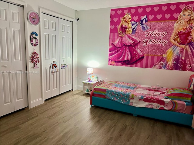 bedroom featuring wood-type flooring and multiple closets