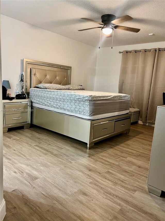 bedroom featuring light wood-type flooring, a textured ceiling, and ceiling fan