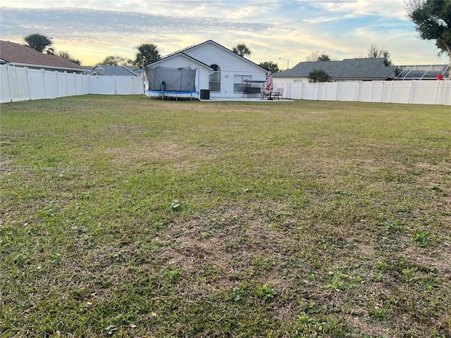 yard at dusk with a trampoline and a patio area