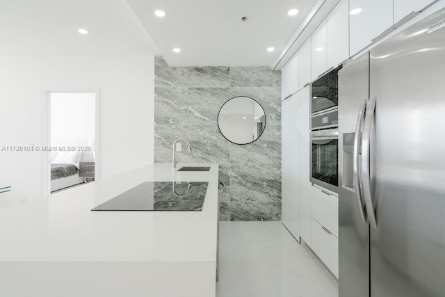 kitchen featuring sink, white cabinetry, appliances with stainless steel finishes, and tile walls