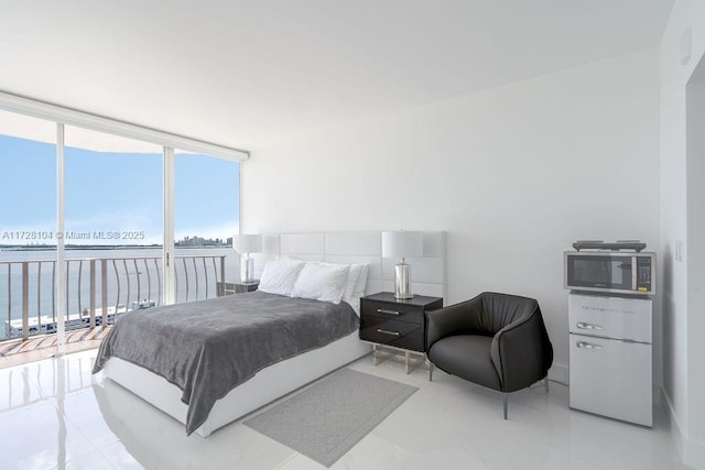 bedroom featuring a wall of windows and a water view