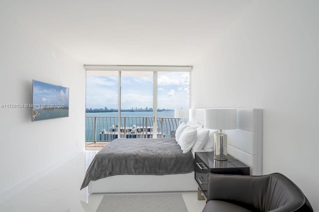 bedroom with a water view, a wall of windows, and access to exterior