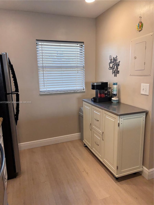 kitchen featuring white cabinetry, stainless steel fridge, light wood-type flooring, and electric panel