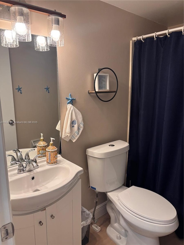 bathroom with toilet, vanity, and curtained shower