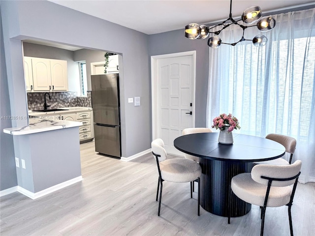 dining room with sink, a chandelier, and light hardwood / wood-style flooring