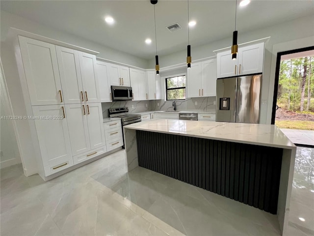 kitchen with pendant lighting, a kitchen island, white cabinetry, stainless steel appliances, and tasteful backsplash