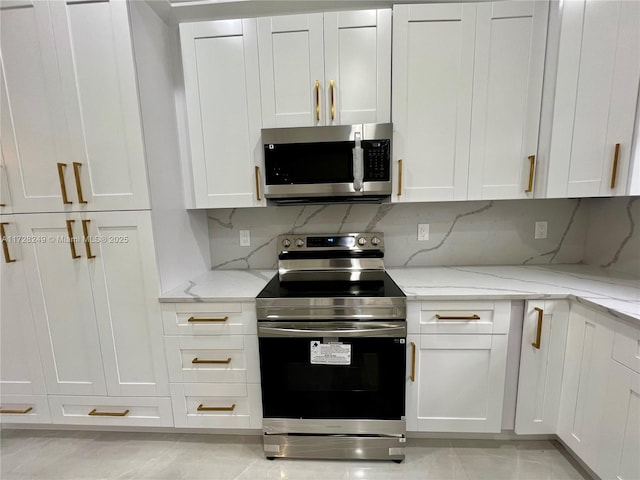 kitchen featuring light stone countertops, backsplash, appliances with stainless steel finishes, and white cabinetry