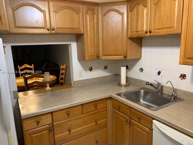 kitchen with backsplash, sink, and white appliances