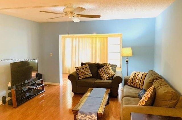 living room featuring ceiling fan, wood-type flooring, and a textured ceiling