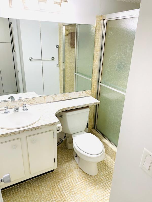 bathroom with a shower with shower door, toilet, and vanity