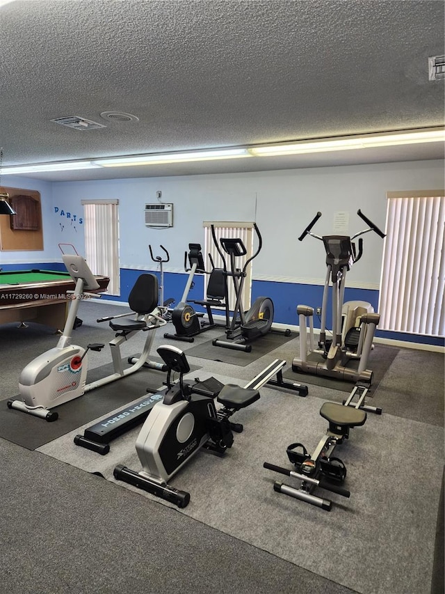 gym featuring a textured ceiling and a wall mounted air conditioner